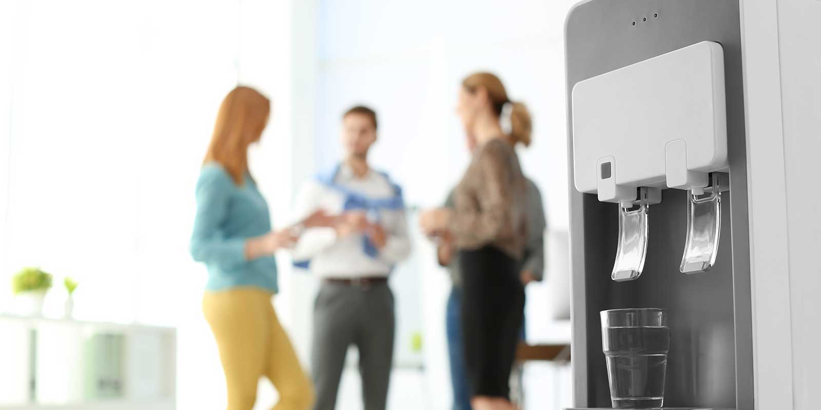 Coworkers gathered around the bottleless undercounter water cooler at work