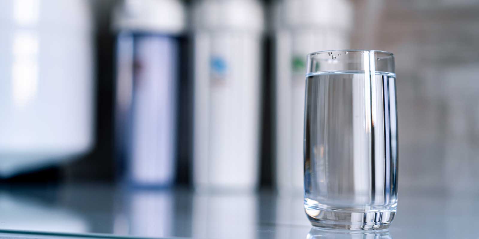 Glass of water in front of a reverse osmosis filtration system
