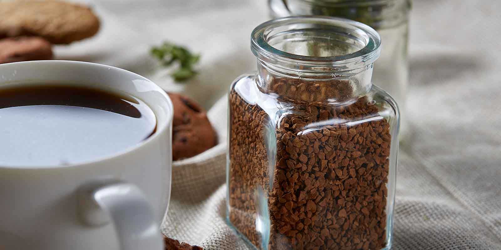 Jar of instant coffee next to coffee cup