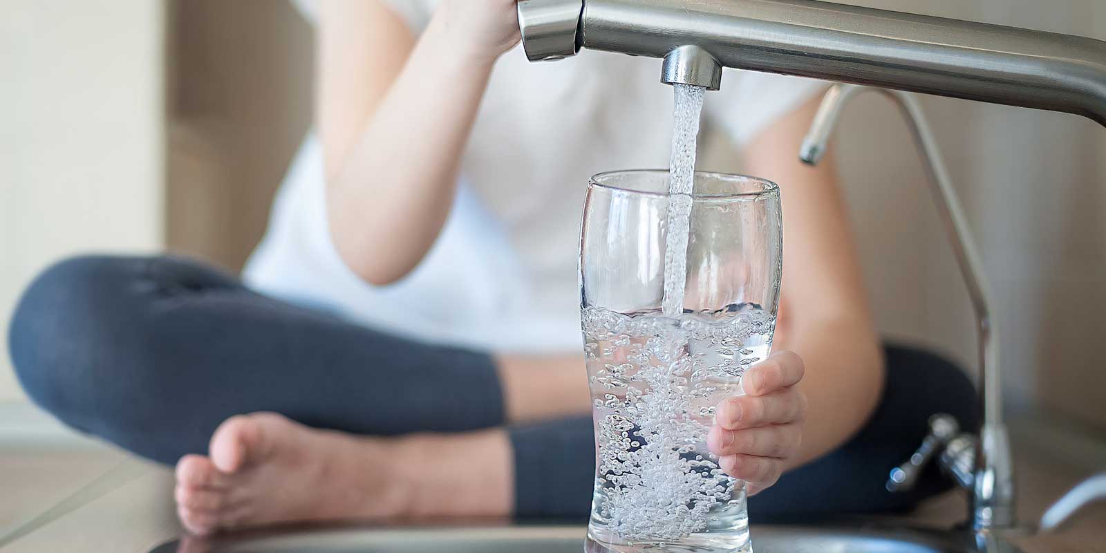 Little girl filling glass from a residential water softening and filtration system