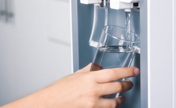 filling glass with water cooler indoors
