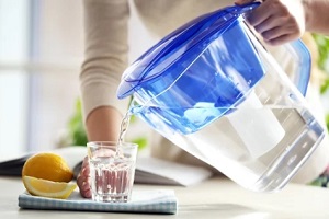 pouring water in glass from big jug