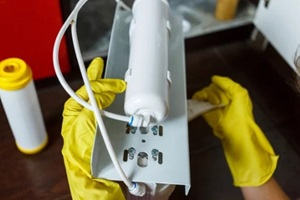 plumber in yellow household gloves changes water filters