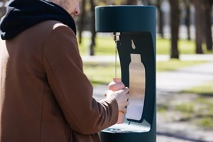 man refilling his water bottle at the city. Free public water bottle refill station