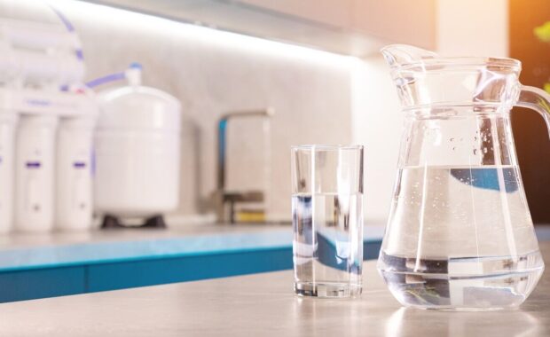 jug and glass of pure water with filteration system in blurred background