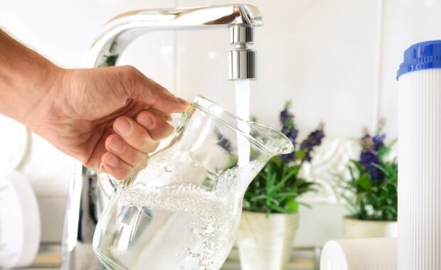 hand filling jug from a tap with filtered osmosis water