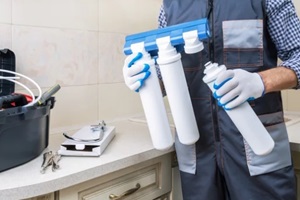 plumber man installs or change water filter in the kitchen