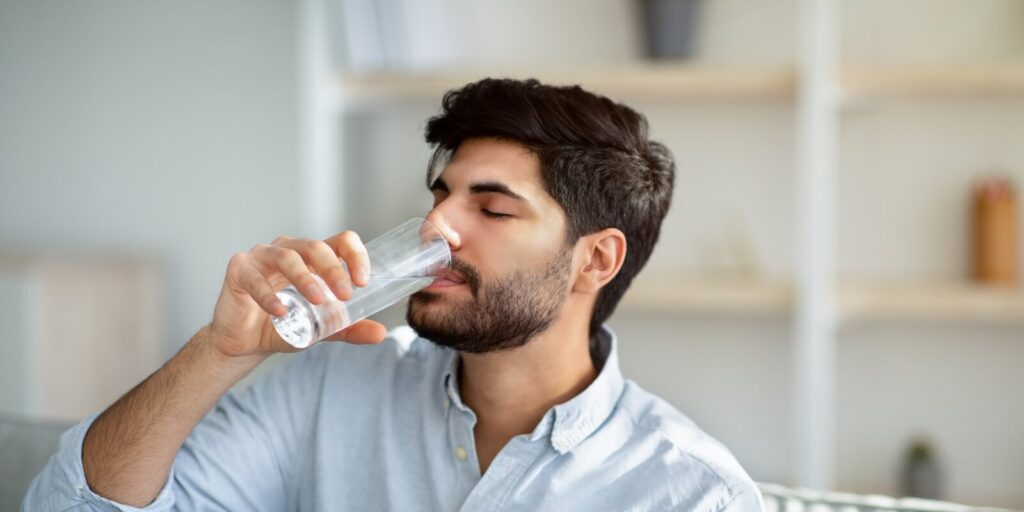 young arab man drinking fresh water from glass