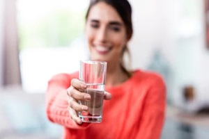 young woman showing drinking glass with water