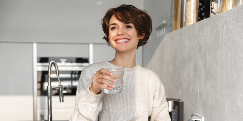 smiling young woman holding glass of water