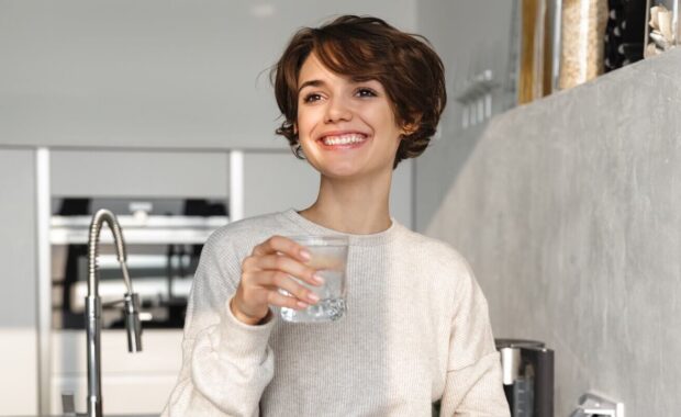 smiling young woman holding glass of water